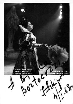 a black and white photo of a woman in an elaborate dress with her arms outstretched