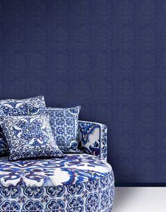 a blue and white couch sitting in front of a wall with decorative pillows on it