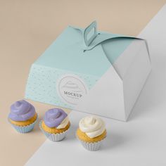 three cupcakes sitting in front of a blue and white box with the word mockup on it