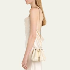 Jimmy Choo "Bon Bon" bucket bag in allover pearly satin viscose, brass, and ABS Flat metal top handle  Drawstring closure  Approx. 5.9"h x 5.5"W x 3.7"D Item Weight (Lbs.): 1.0 Made in Italy Chic Bucket Bag With Pearl Handle, Bucket Bag With Pearl Handle, White Bucket Bag For Evening, Chic Gold Bucket Bag For Evening, Elegant Beige Bucket Bag For Party, Elegant Bucket Bag For Events, Cream Evening Bucket Bag In Pouch Shape, Formal Bucket Shoulder Bag With Pearl Handle, Cream Evening Bucket Bag Pouch