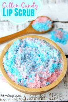 two wooden spoons filled with colored powder on top of a white table next to some pink and blue sprinkles