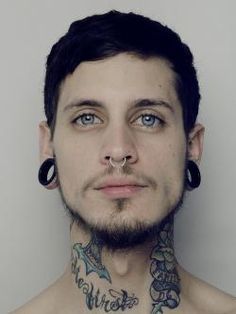 a man with tattoos on his chest and nose