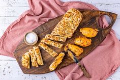 some food is laying on a wooden cutting board with a knife and spoon next to it