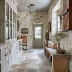 an old stone house with white cabinets and wood accents on the walls, along with a wooden bench