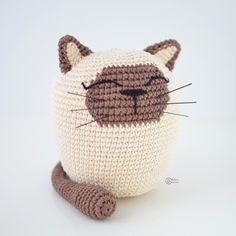 a crocheted cat pillow sitting on top of a white table