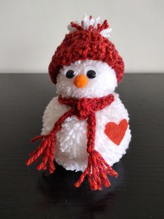 a small white snowman with a red hat and scarf