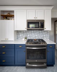 a stove top oven sitting inside of a kitchen next to white cabinets and blue drawers