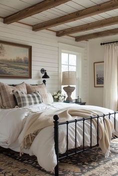 a bedroom with white walls, wood beams and a black iron bed in the middle