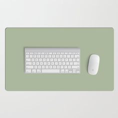 a computer keyboard and mouse sitting on a green surface with a white mouse pad in front of it