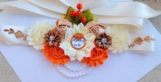 an orange and white flower headband on top of a piece of paper with pearls