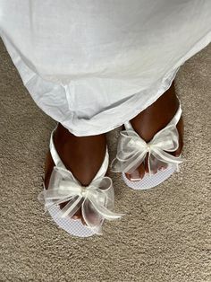 a close up of a person wearing white shoes with bows on their ankles and feet