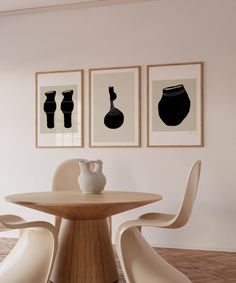 three framed black and white vases sit on a table in front of two chairs