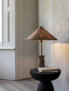 a lamp sitting on top of a black table next to a book and a window