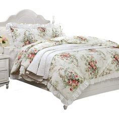 a white bed sitting next to a night stand with flowers on it and two nightstands