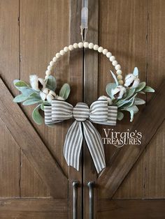 a wreath with white flowers and greenery hangs on a door handle in front of a barn door