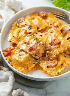 a white plate topped with ravioli and meat covered in cheese on top of a marble table