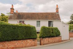 a white house surrounded by hedges and trees