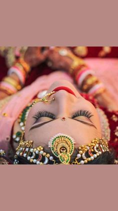 a close up of a woman's face with makeup and jewelry on her head