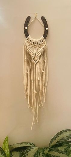 a wall hanging made out of rope and leather with a wooden hook attached to it