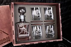 an open wooden box containing six glasses and a decanter in which the contents are engraved