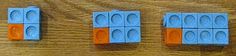 three blue and orange lego blocks on a wooden surface