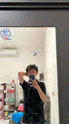 a young man taking a selfie in front of a mirror with his cell phone