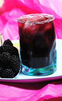 there is a drink with blackberries on the plate