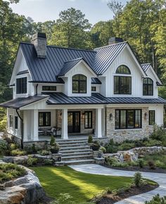 a large white house with black roof and stone steps leading up to the front door