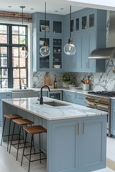 a kitchen with blue cabinets and marble counter tops, two stools at the island