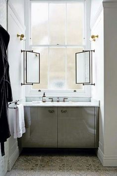 a bathroom with a sink, mirror and towels hanging on the rack in front of it