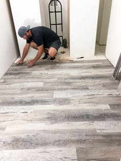 a man kneeling down on the floor in front of a wall with wood planks