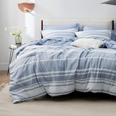 a bed with blue and white striped comforters in a room next to a lamp