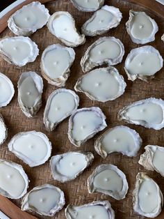 several open oysters sitting on top of a wooden tray with white sauce in them