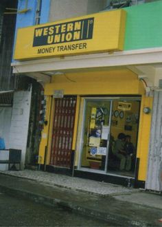 a man is standing in the doorway of a money transferer store that has been painted yellow and green