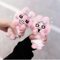 two pink teddy bears with bows on their heads are being held by someone's hand