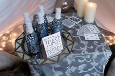 there are some bottles that are on the table with candles in front of them and a sign reading toast friends