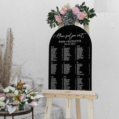 a wooden easel with seating chart and flowers on it next to a planter