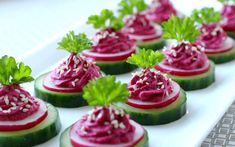 cucumbers with red sauce and parsley are arranged on a white platter