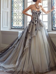 a woman standing in front of a window wearing a dress