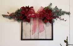 a christmas decoration with poinsettis and greenery hangs on the wall