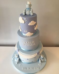 a three tiered blue and gray cake with a teddy bear topper on it