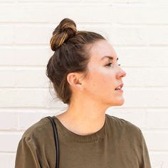 a woman standing in front of a white brick wall