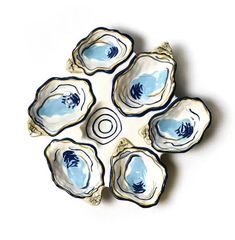 four blue and white dishes sitting on top of each other in the shape of seashells