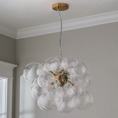 a chandelier hanging from the ceiling in a room with white walls and windows