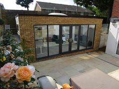 an outdoor living area with patio furniture and flowers in the foreground, surrounded by brick buildings