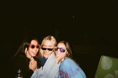 three girls are posing for the camera with their sunglasses on