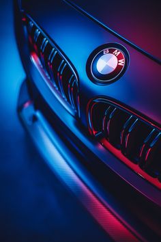 the front end of a bmw car with red and blue light coming from it's grille