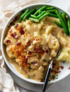 a bowl filled with mashed potatoes, green beans and meat covered in gravy