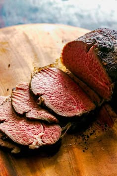 sliced meat sitting on top of a wooden cutting board