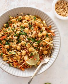 a white bowl filled with food next to two bowls of peanuts and limes on the side